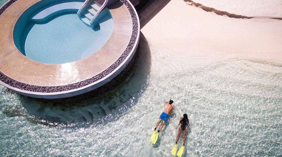 couple swimming in ocean next to pool